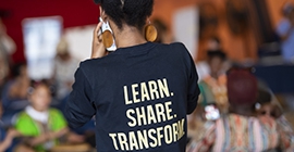 a female with pack turned wearing a shirt that says, " LEARN. SHARE. TRANSFORM"